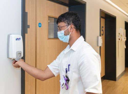 Man putting on hand gel and wearing PPE