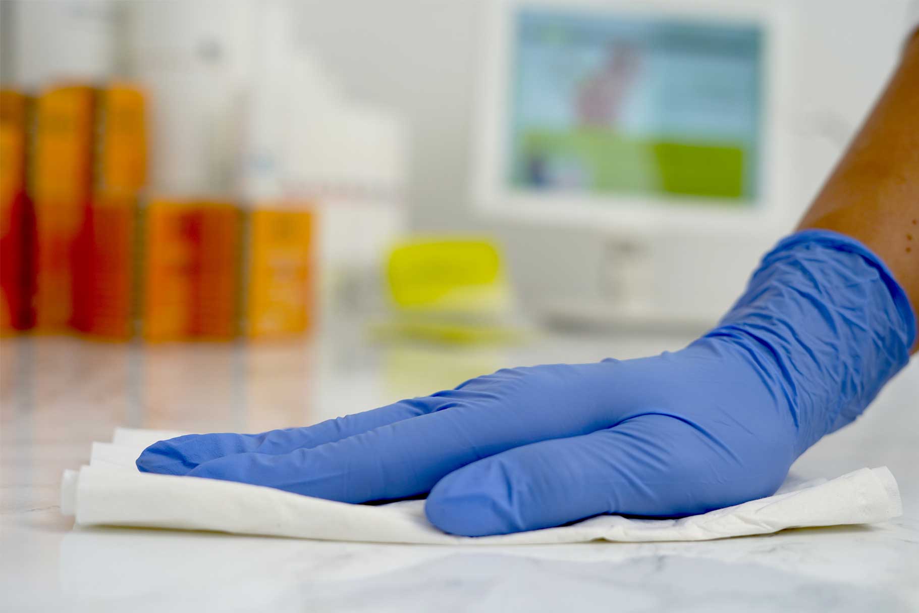A surgical gloved hand wiping a surface