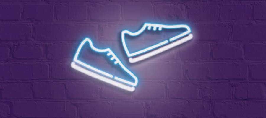 Illuminated trainers walking against brick wall