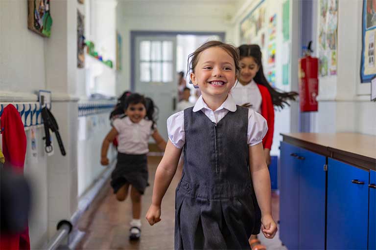 Happy primary pupil walking down corridor
